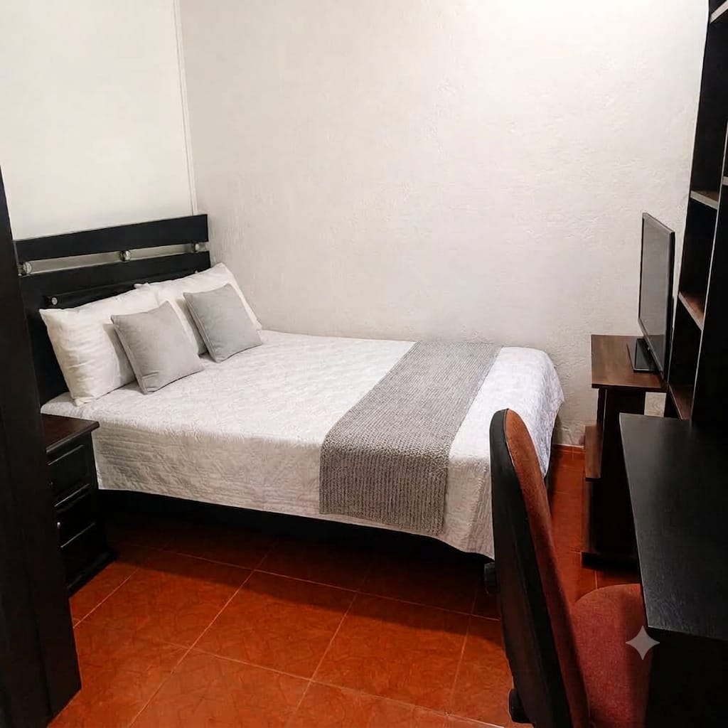 Habitación Urban con cama, televisor y zona de escritorio en madera.